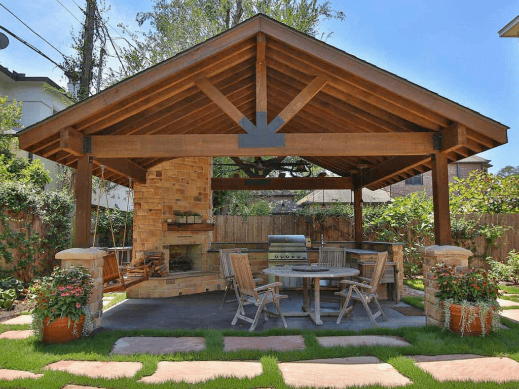 Beautiful outdoor living design in a homeowners backyard consisting of a patio, kitchen, furntiture, and pavillion