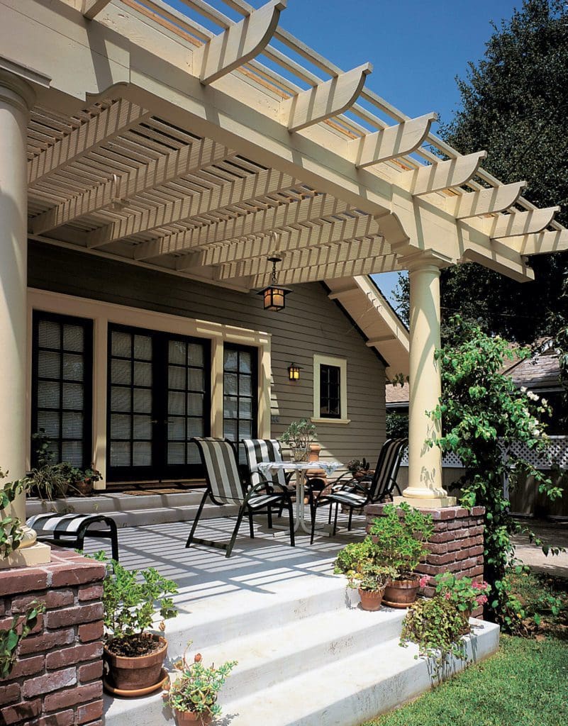 painted pergola attached to house over a concrete patio