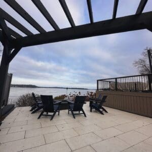 Modern Patio Lake View with Pergola Unilock Soreno Toscana Beige modern patio with lake view and all black pergola overhead